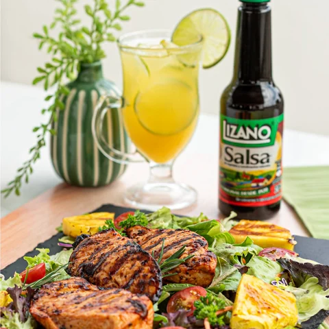 A Lizano bottle alongside a grilled meal